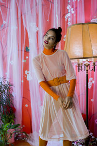 Young woman standing against curtain