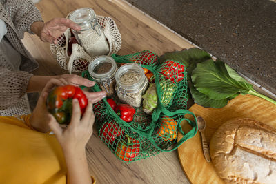 Grandmother and granddaughter unpacking fresh groceries in kitchen