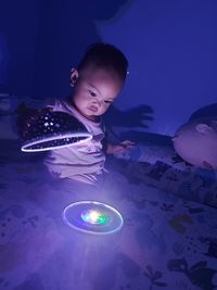 Side view of baby girl playing lamp at the bed