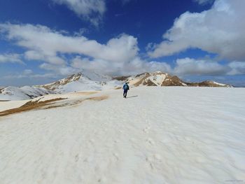 Man climbing on land against sky