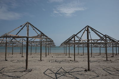 Metallic structure on beach against sky