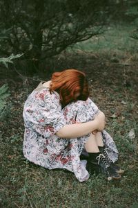 Rear view of woman sitting on field