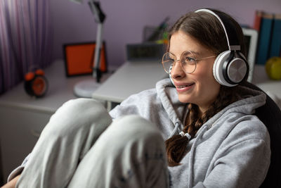 Smiling teenager listening to music on wireless headphones.