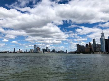 Sea by buildings in city against sky