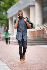 Full length portrait of young man standing on footpath