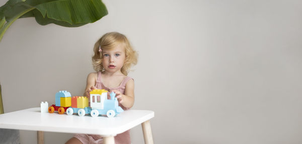 Pretty caucasian 1,2 year old with blond curly hair playing with colourful construction cubes, toys