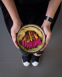 Low section of woman holding sliced fruits in bowl