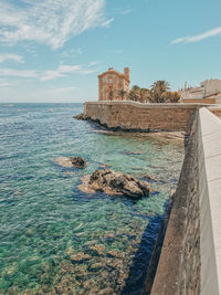 Old building by sea against sky