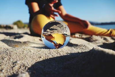 Close-up of hand holding shell by sea against sky