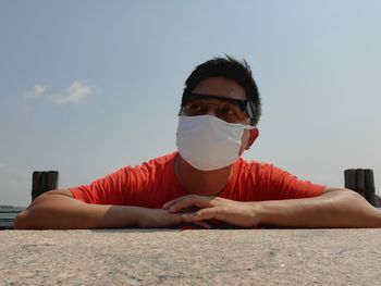 Portrait of young man wearing sunglasses sitting against sky