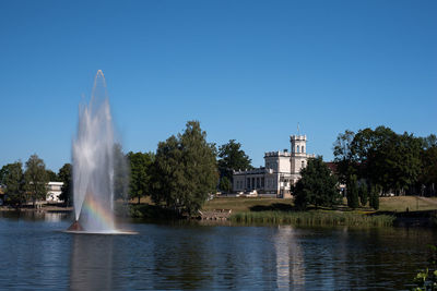 Fountain in lake against clear sky