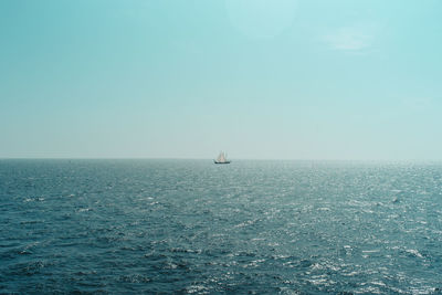 Scenic view of sea against clear sky with small yacht