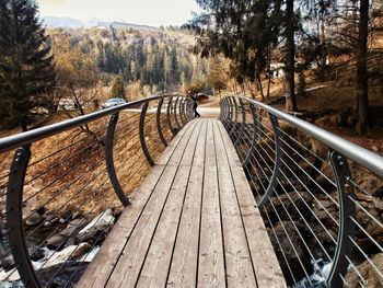 Footbridge amidst trees against sky