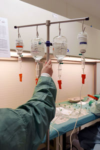 Cropped hand on doctor holding iv drip stand in wardroom at hospital