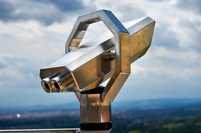 Close-up of metallic coin-operated binoculars against sky