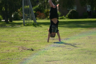 Boy performing handstand on field in park