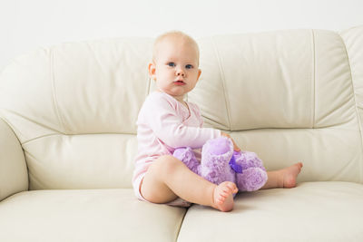 Cute baby girl sitting on sofa at home