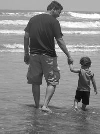 Rear view of father and daughter on beach