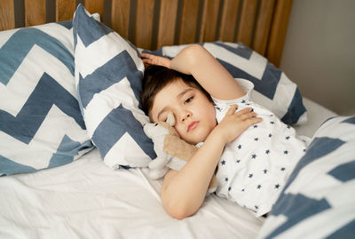 Boy sleeping on bed at home