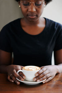 Midsection of man holding coffee cup on table