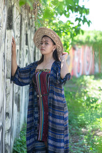 Young woman standing against trees