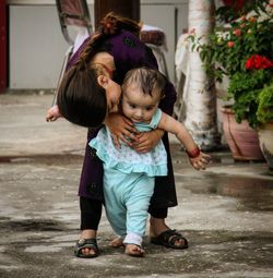 Sister kissing toddler while walking on footpath