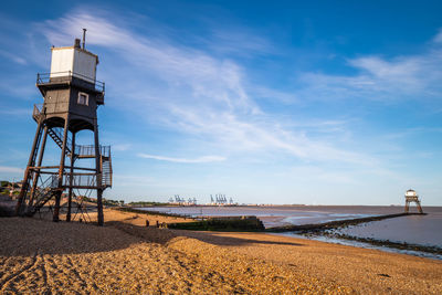 Lighthouse by sea against sky