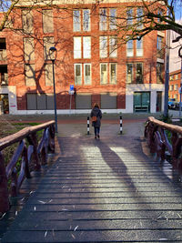 People walking on footpath by buildings in city