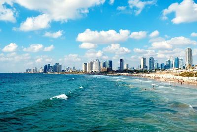 Sea by buildings in city against sky