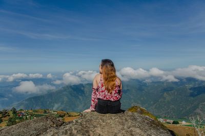 Rear view of woman standing on mountain against sky