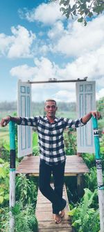 Portrait of man standing by plants against sky