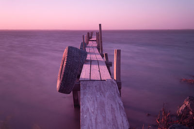 Tires hanging on old wooden jetty over salton sea lake against sky