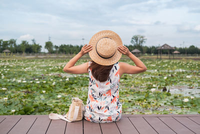 Rear view of woman in hat standing against sky