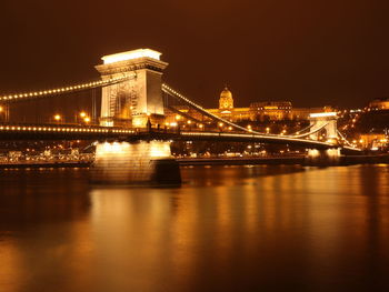 Illuminated bridge over river at night