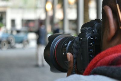 Close-up of man photographing through camera in city