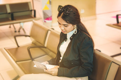 Young woman holding passport while sitting in airport