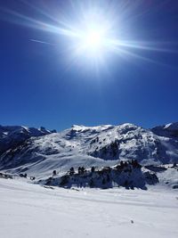 Scenic view of snowcapped mountains against sky on sunny day