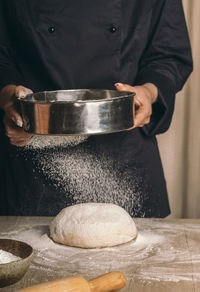 A woman rubs the dough through a sieve close-up. chef prepares dough for cake, festive dinner