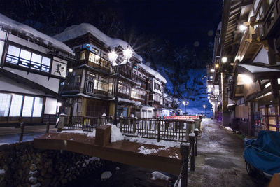 Illuminated street amidst buildings in city during winter