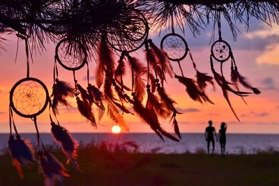 Close-up of dreamcatchers with couple in background at beach