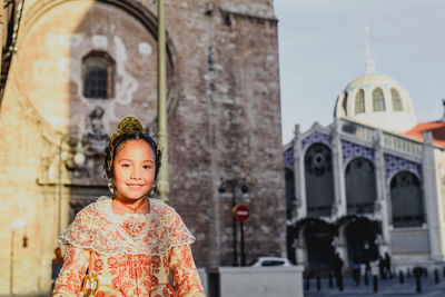 Portrait of woman standing against building