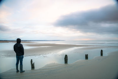 Man standing on beach against sky during winter