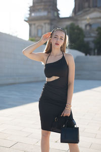 Portrait of young woman standing in city