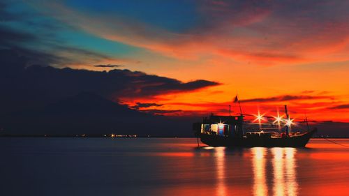 Boat sailing in sea against sky at sunset