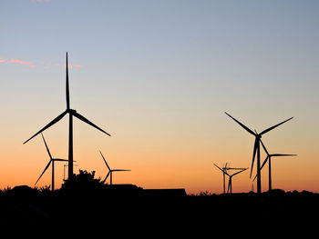 Silhouette windmill on field against sky during sunset