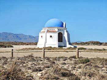 Built structure on field against clear blue sky