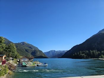 Scenic view of sea and mountains against clear blue sky