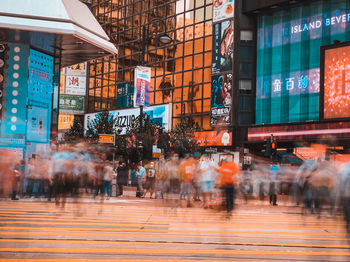 People walking on illuminated street amidst buildings in city
