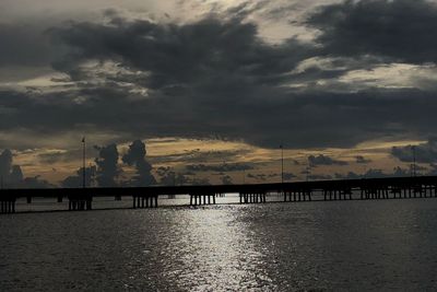 Silhouette pier over sea against sky during sunset