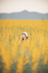 Young woman photographing on field